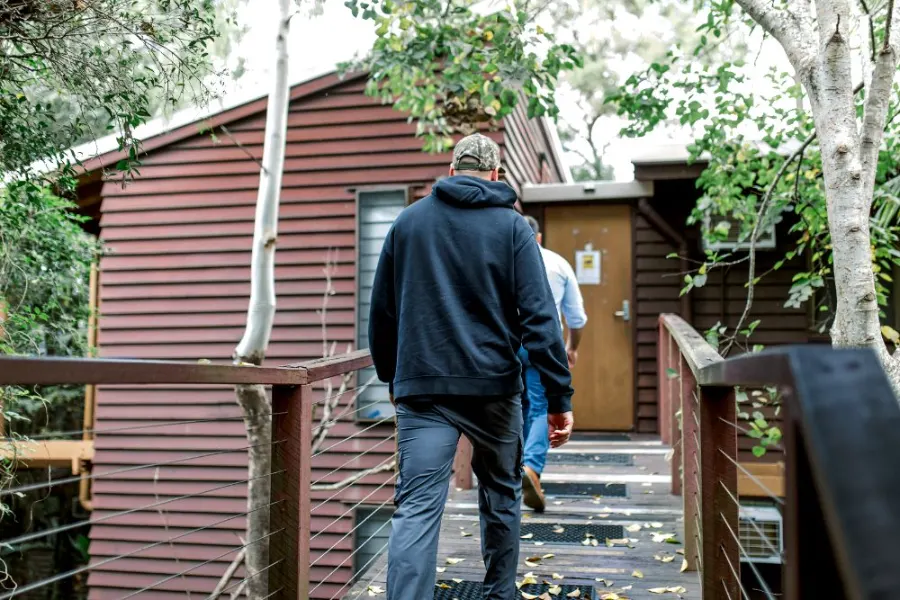 Veterans walking to a residential cabin surrounded by bushland